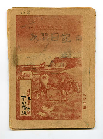 海岸で放牧される牛と座って本を読む少年のイラストが描かれたノートの表紙の写真