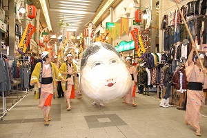 大須のお鍬祭りで商店街を練り歩く、大きなおたふくの造り物を持った博物館職員有志の行列