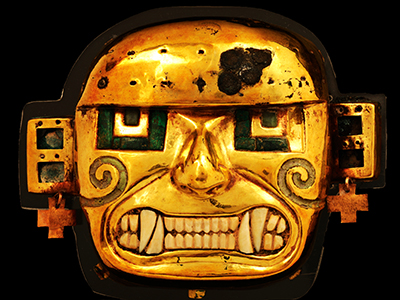 目と歯に象嵌細工の施された男性の顔の金属製マスクの写真
目に緑色の石と歯に貝殻をはめ込んだ男性の顔の金属製マスクの写真