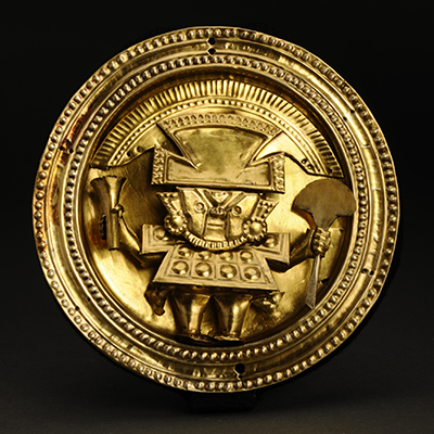 中央にシカン王の像が打ち出された円形の金の装飾品の写真