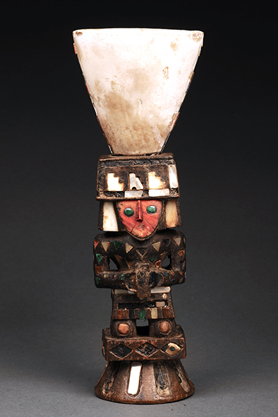 木彫りの人形に貝殻や鉱物で装飾を施したコップの写真