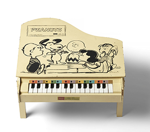 木でできたおもちゃのピアノ。ピアノにはヴァイオリンを弾くスヌーピーと仲間たちが描かれる。