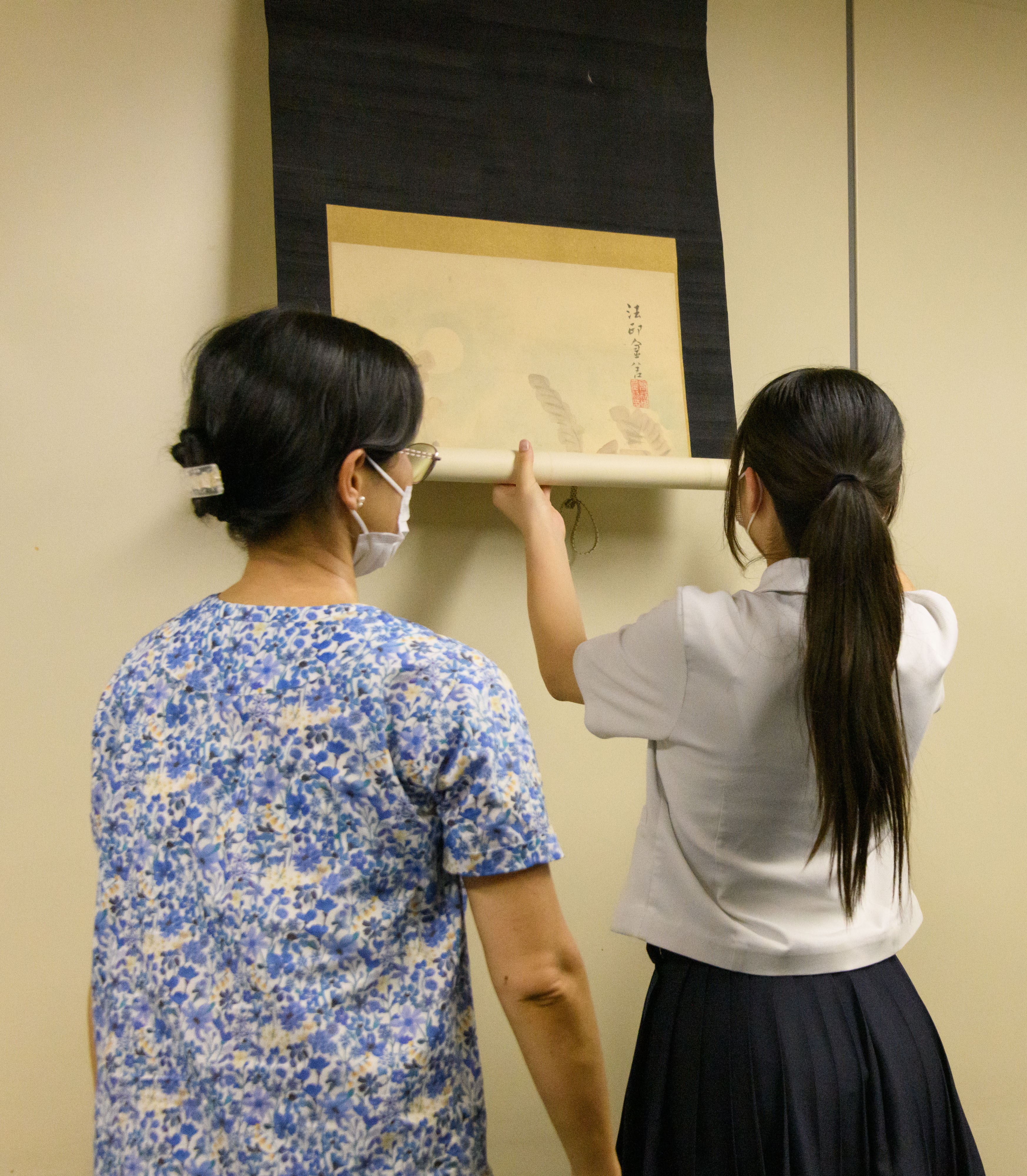 学芸員と、掛軸の取り扱いを体験する中学生