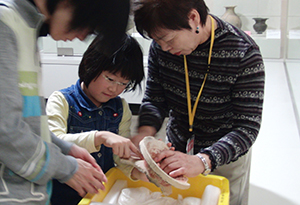 土器を手にとって見る女性と子ども