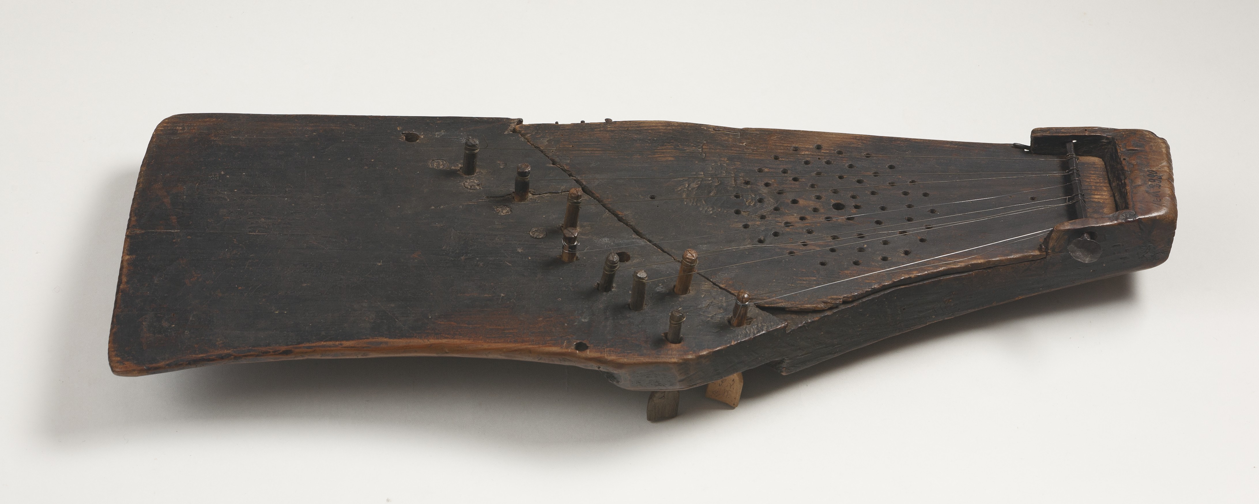 A trapezoidal stringed instrument made of dark wood