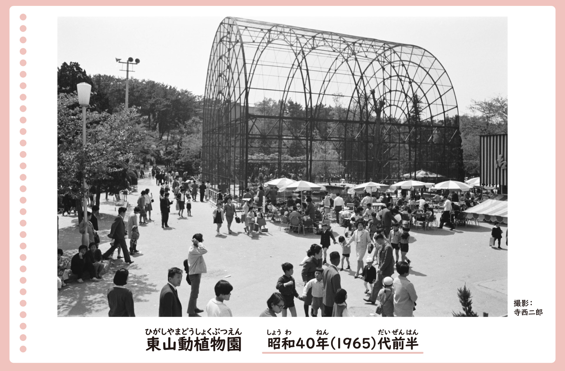 東山動植物園の中の風景。大きなアーチ型の檻の周りで大勢の人が集まっている。檻の近くにはパラソルがあり、来場者が休んでいる。
