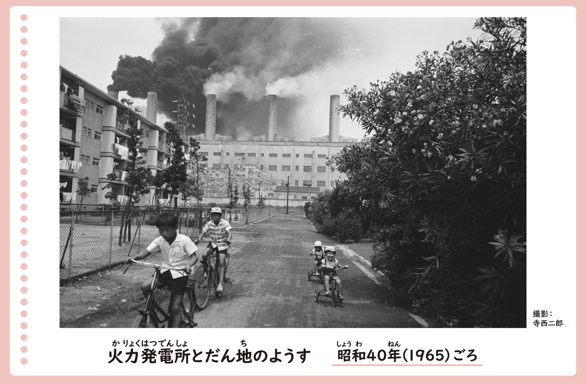 名古屋港付近の火力発電所と団地の風景。昭和40年ごろ。団地のそばに大きな煙突が何本も建ち、煙が立ち上っている。団地横の道を子供が自転車に乗って走っている。